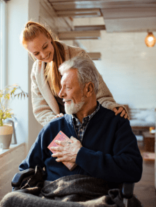 Woman nurse helping old man in a wheelchair in his home