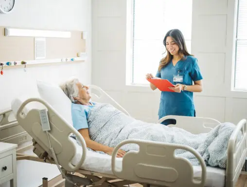 Young woman nurse chatting with her elderly woman patient