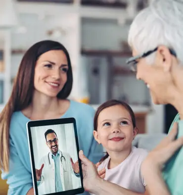 Mother and Daughter helping the grandmother do a telehealth visit on the ipad